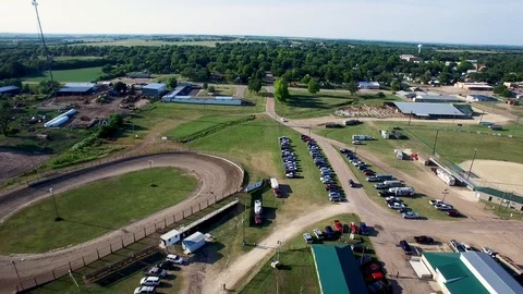 Aerial pull back from dirt track to reveal equestrian centers, builds Stock Footage 107142673