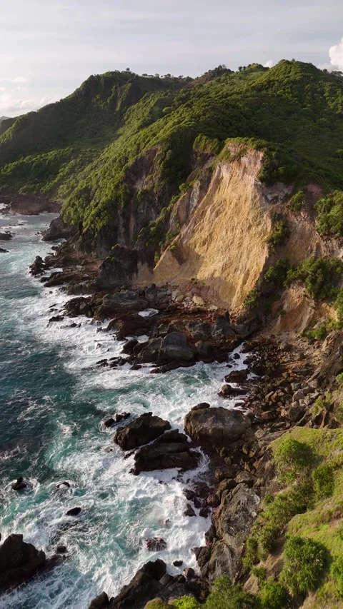 Aerial pull back from Lombok cliffs and crashing waves, Indonesia, 4K vertical Stock Footage 346061804