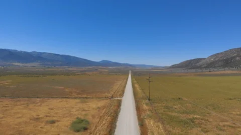 Aerial-Pull Back-A long straight mountain valley road with vanishing point Stock Footage 112361023