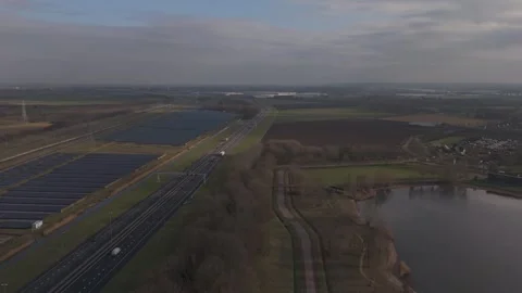 Aerial pull-back motion of Dutch solar farm, highway and windmills Stock Footage 330189808