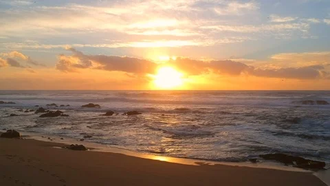Aerial pull back over beach at sunset over ocean in summer Stock Footage 95135690