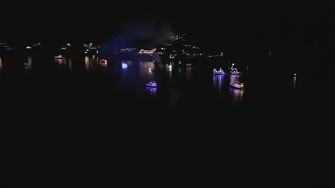 Aerial pull back over a Christmas fireworks scene boat light parade in harbor Stock Footage 262803436