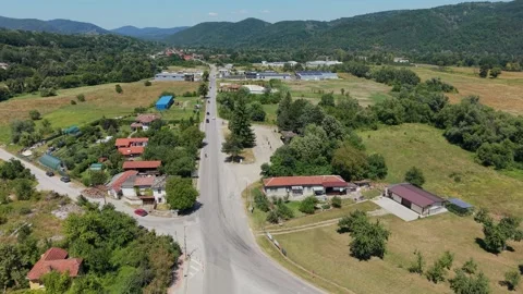 Aerial pull back over the main road of a Bulgarian village Stock Footage 344626931