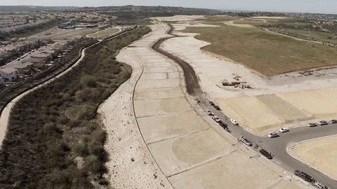 Aerial pull back over plots of new development housing with buildings to Stock Footage 99382404