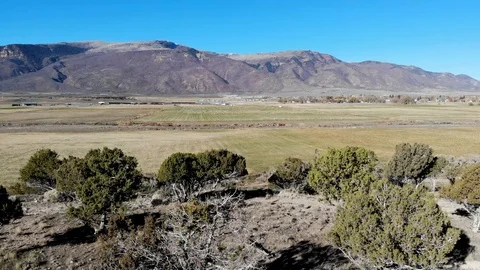 Aerial-Pull back over sagebrush and juniper hills view fields distant mountains Stock Footage 97911355