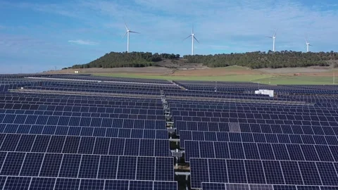 Aerial pull back over solar panels with wind turbines in background Stock Footage 327812303