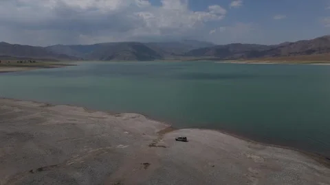 Aerial pull back over a turquoise reservoir and its shoreline, Kyrgyzstan Stock Footage 347240334