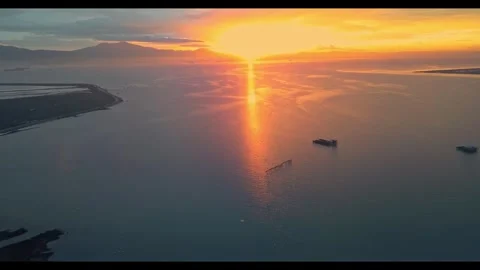 Aerial pull-back over vast wetlands revealing coastal road at golden sunset Stock Footage 345963099
