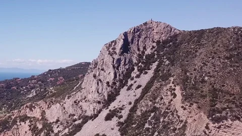 Aerial pull back from a peak with runs of a Tower on a cliff by the sea Stock Footage 107189485