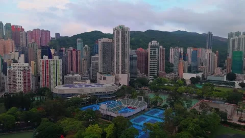 Aerial pull back rising above Victoria Park pool and tennis courts toward Hong Stock Footage 336341272