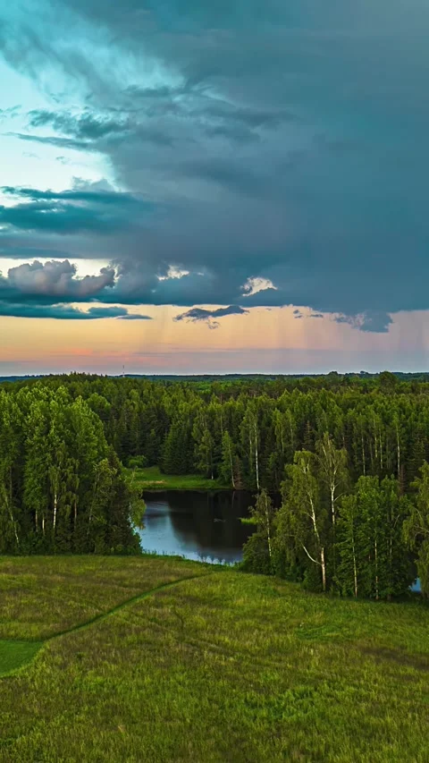 Aerial pull back shot of dense clouds passing over alpine forest during sunset Video stock 300243651