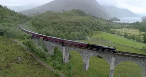 Aerial pull back shot of The Jacobite Express Crossing the Glenfinnan Video stock 169062519