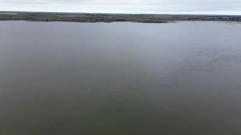Aerial pull-back shot over a vast, moody lake on a cloudy day. Stock Footage 312417403