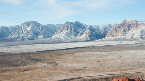 Aerial pull back shot of snow covered mountains and colorful sandstone cliffs Stock Footage 122055595