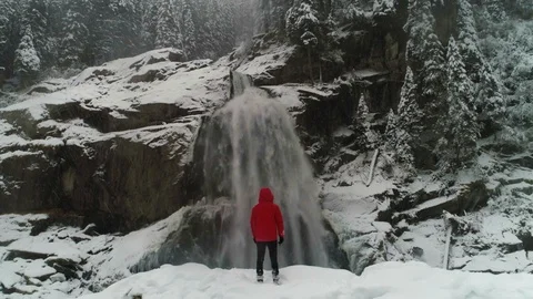 Aerial pull back shows scale of person in front of waterfall Stock Footage 102421706