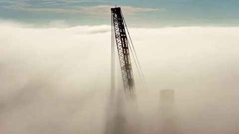 Aerial Pull Back of Silhouetted Crane Building Wind Turbine in Clouds at Sunset Video stock 315260799