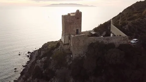 Aerial pull back - sunset over the sea with medieval tower in foreground Stock Footage 104490914