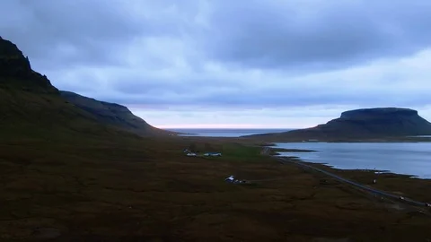 Aerial pull back view of a fjord in West Iceland at sunset revealing a waterfall Stock Footage 115712855