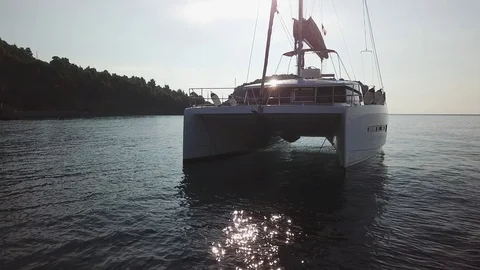 Aerial pull back view, grazing flight from a Catamaran anchored with reflections Stock Footage 96374150