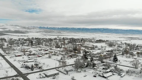 Aerial-Pull Back view of snowy small town and distant mountains Stock Footage 99479541