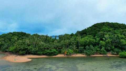Aerial pull back from wild coconut palms revealing small island 4K Stock Footage 336886962
