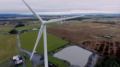 Aerial pull back from wind turbine generating renewable energy over farmland in  Vídeos de archivo 328459999