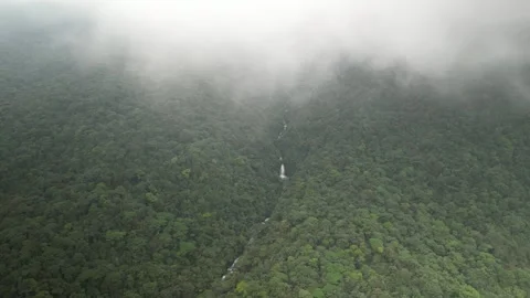 Aerial pull out shot of Rio Celeste and waterfall with low clouds in Costa Rica Stock Footage 329656509