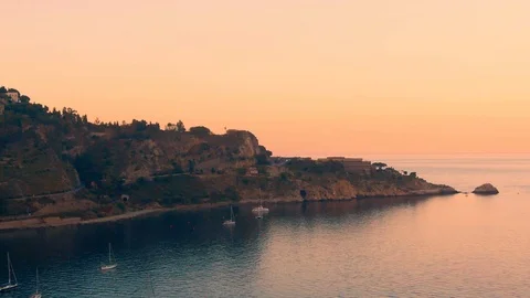 Aerial pull out view of the beach at Capo Taormina in Sicily at sunset Stock Footage 110803514