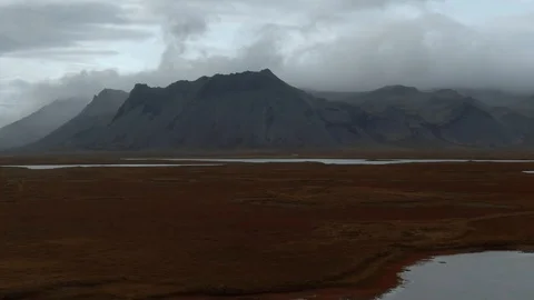 Aerial pull out view of volcanic mountains with clouds in West Iceland Video stock 118443661