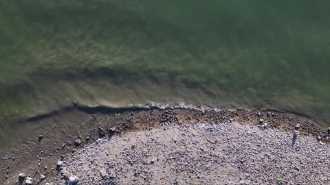 Aerial Pull-Up Shot of a River Washing Over a Rocky Shoreline Stock Footage 314076838