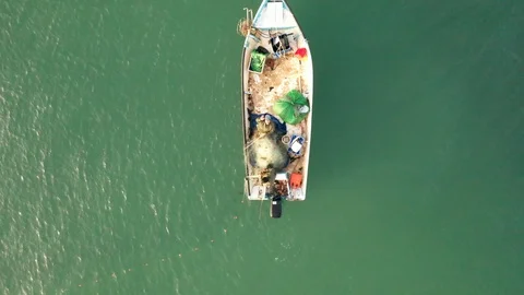 Aerial pull up top down shot of fishermen wave hello, small fish boat in Stock Footage 120473482