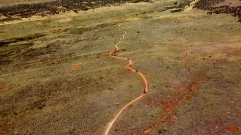 Aerial pullaway shot of single file mountain bikers riding on a trail in CO Stock Footage 247363656