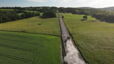 Aerial, pullback country road, tractor and trailer leave dust cloud, summer. Stock Footage 155586632