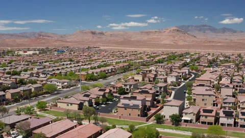 Aerial pullback drone shot of Las Vegas suburban homes and roofs of mountains Stock Footage 308819616