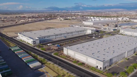 Aerial pullback drone shot of North Las Vegas warehouses with distant skyline 스톡 동영상 333523542