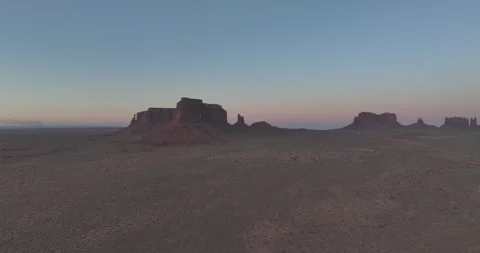 Aerial pullback from Eagle Mesa in Monument Valley under pink sky Видео 346650584