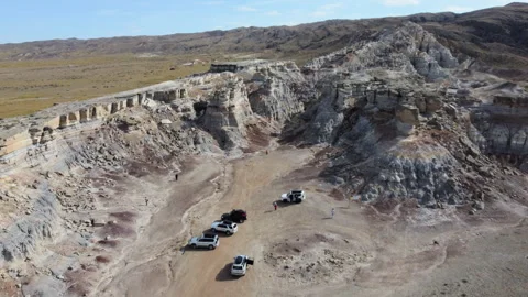 Aerial pullback from eroded white cliffs revealing tourist vehicles in Kokala 스톡 동영상 348250642