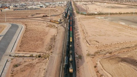 Aerial pullback follow shot of freight hauling train on railroad across USA Stock Footage 121644240