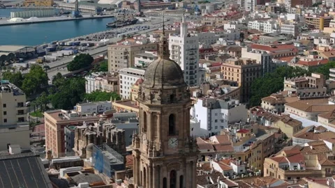 Aerial pullback from Malaga cathedral rising view reveals harbor port and open Stock Footage 334633637