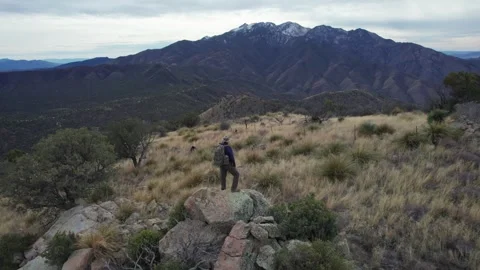 Aerial pullback of a man on a mountain top taking in the view Stock Footage 327872972