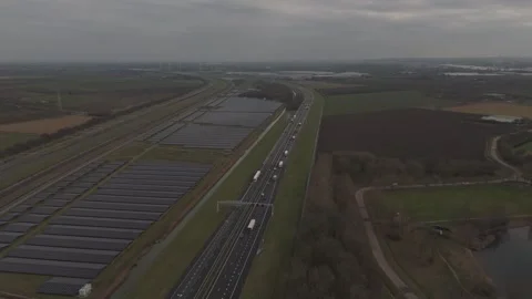 Aerial pullback movement of solar farm near highway and railway Видео 330189919