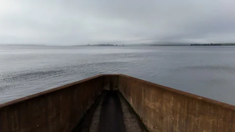 Aerial pullback over dam reservoir revealing spillway and rural wetland Stock Footage 331794988