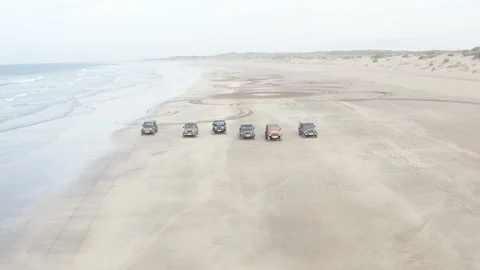 Aerial pullback over six vehicles on a beach at Sidi Rahal Video stock 347848781