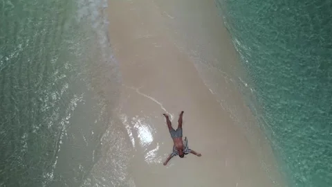 Aerial pullback from relaxed man lying on the famous pristine sandbar of Cayo Vidéo 342957562