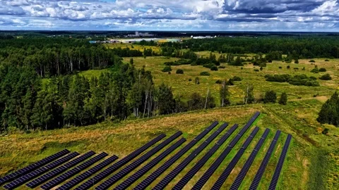 Aerial pullback reveal of vast solar farm in Latvia surrounded by green forest 스톡 동영상 334123961