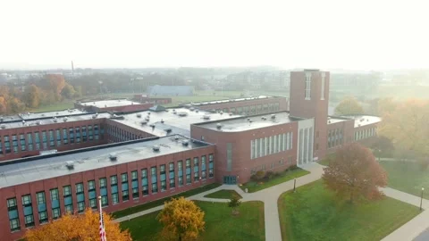 Aerial pullback reveals American flag at large brick school building. Vídeo Stock 143202565