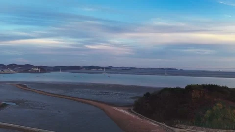Aerial Pullback Reveals Nue Island Sea Road with Still Wind Turbines at Dusk Video stock 334468869
