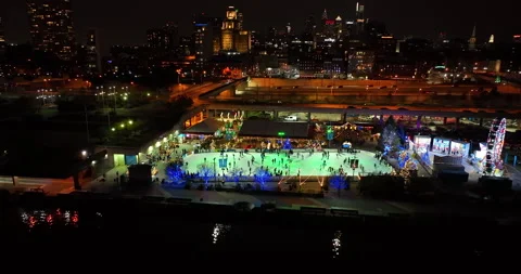 Aerial pullback reveals people ice skating at night on rink by Delware Stock Footage 167622696