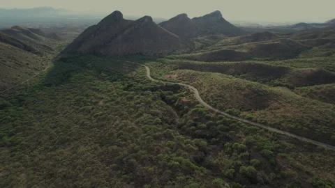Aerial pullback of a road leading to 4 desert mountain peaks Stock Footage 198738749