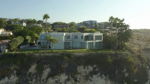 Aerial pullback shot of an amazing cliffside mansion on the beach during the Video stock 96035816